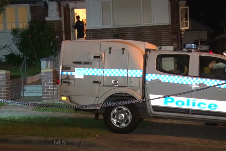 A police car is parked outside a home which is surrounded by police tape.