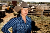 Dakota stands in cattle yards wearing a large hat.