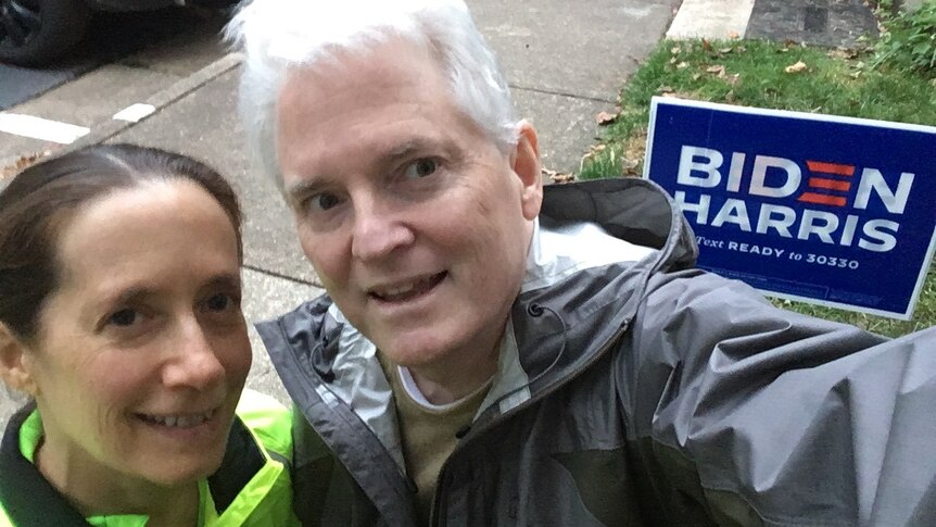 A couple takes a selfie in front of a Biden-Harris lawn sign before the US election.