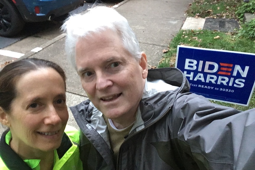 A couple takes a selfie in front of a Biden-Harris lawn sign before the US election.