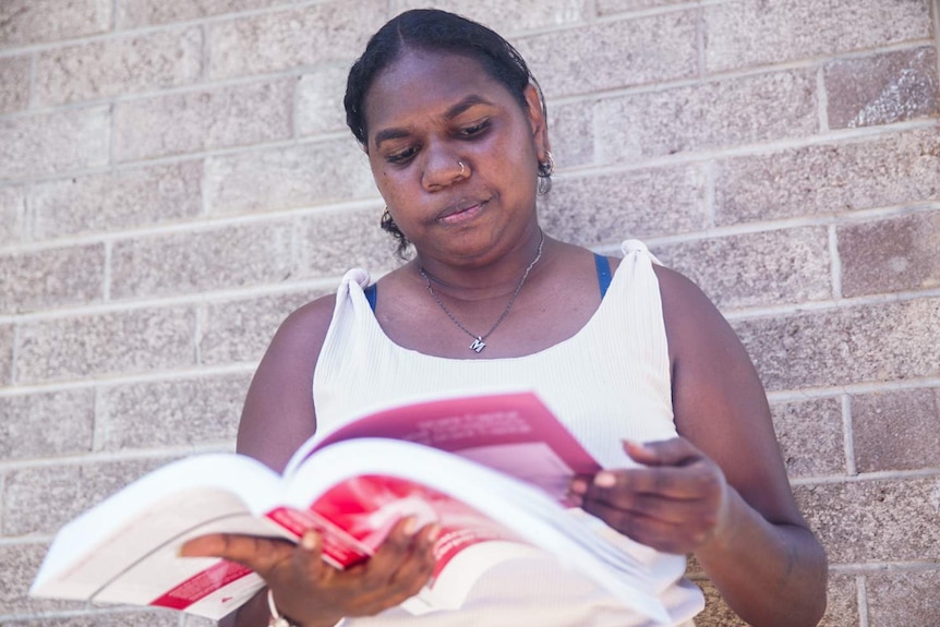 Kenisha Gumbala reads a law book at her home in Darwin.