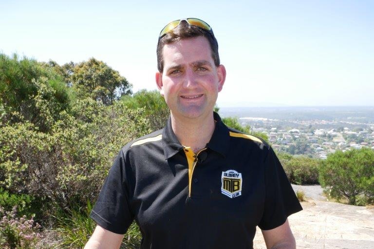 Man stands with his mountain bike on a trail in bushland in Albany.