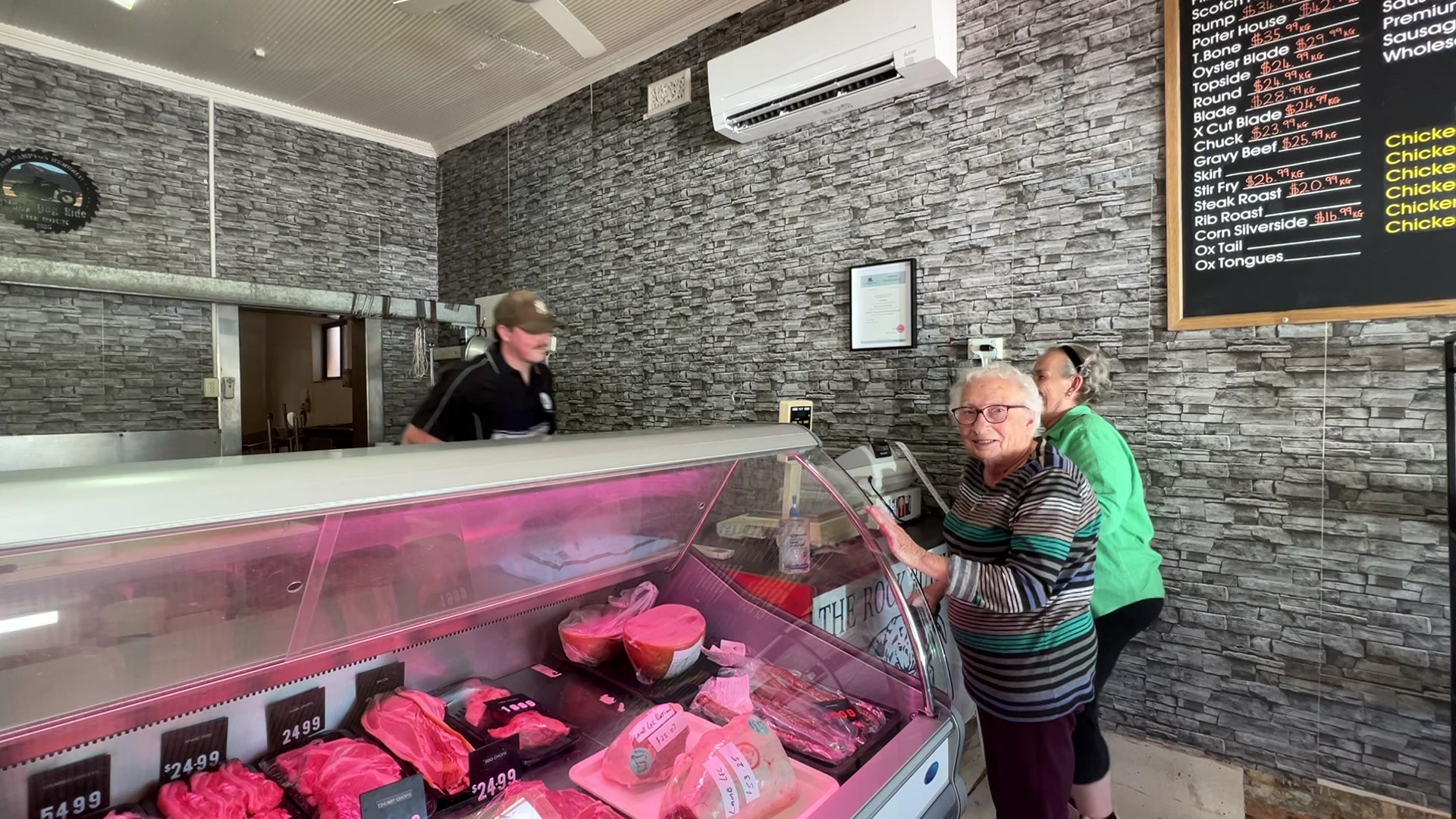 Uma senhora encostada em um armário de açougue