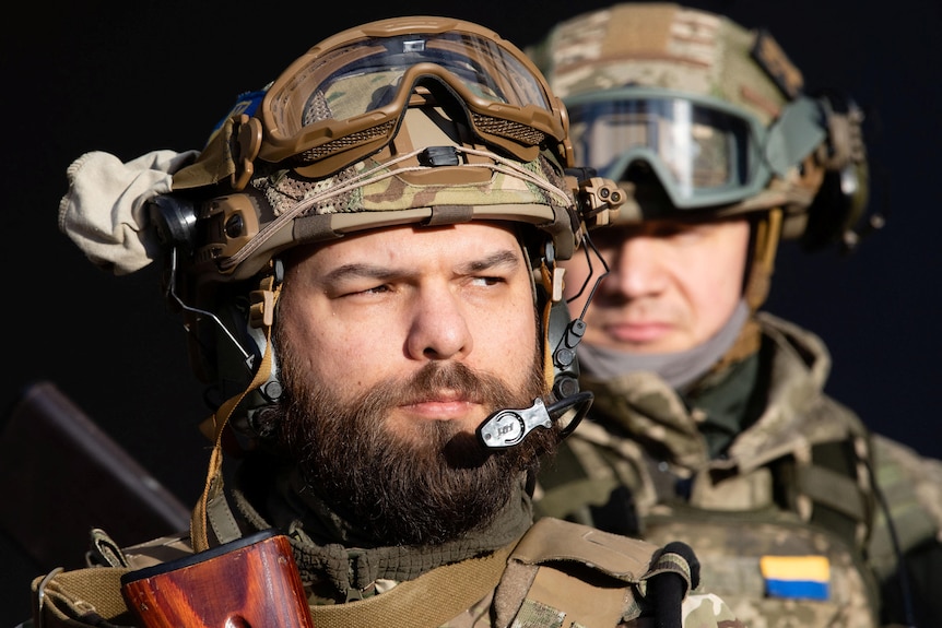 Two Ukrainian men, wearing military uniforms with helmets, goggles and microphones.