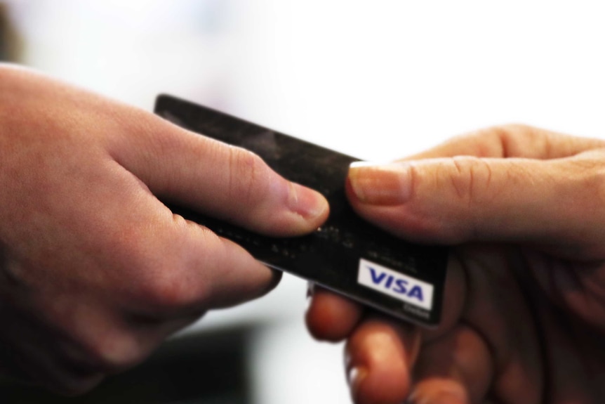 一张信用卡在两人之间交接的特写镜头。