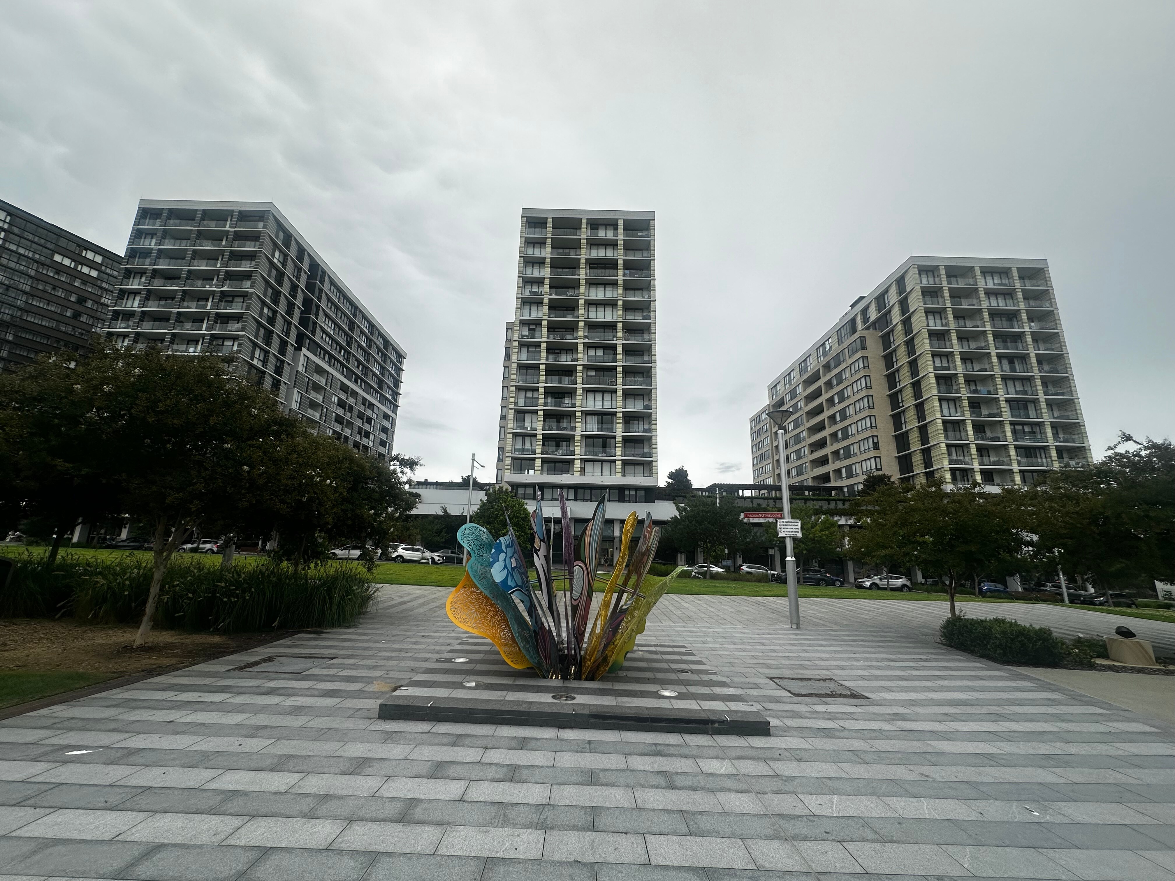 Three buildings visible with a colourful statue in front