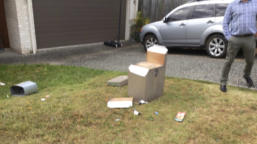 A broken letterbox is strewn over the ground.