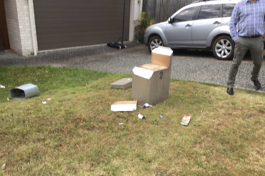 A broken letterbox is strewn over the ground.