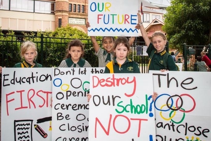 an image of students frowning holding up placards in front of their school