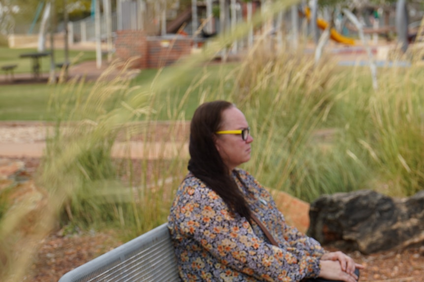 She sits on a bench at a park