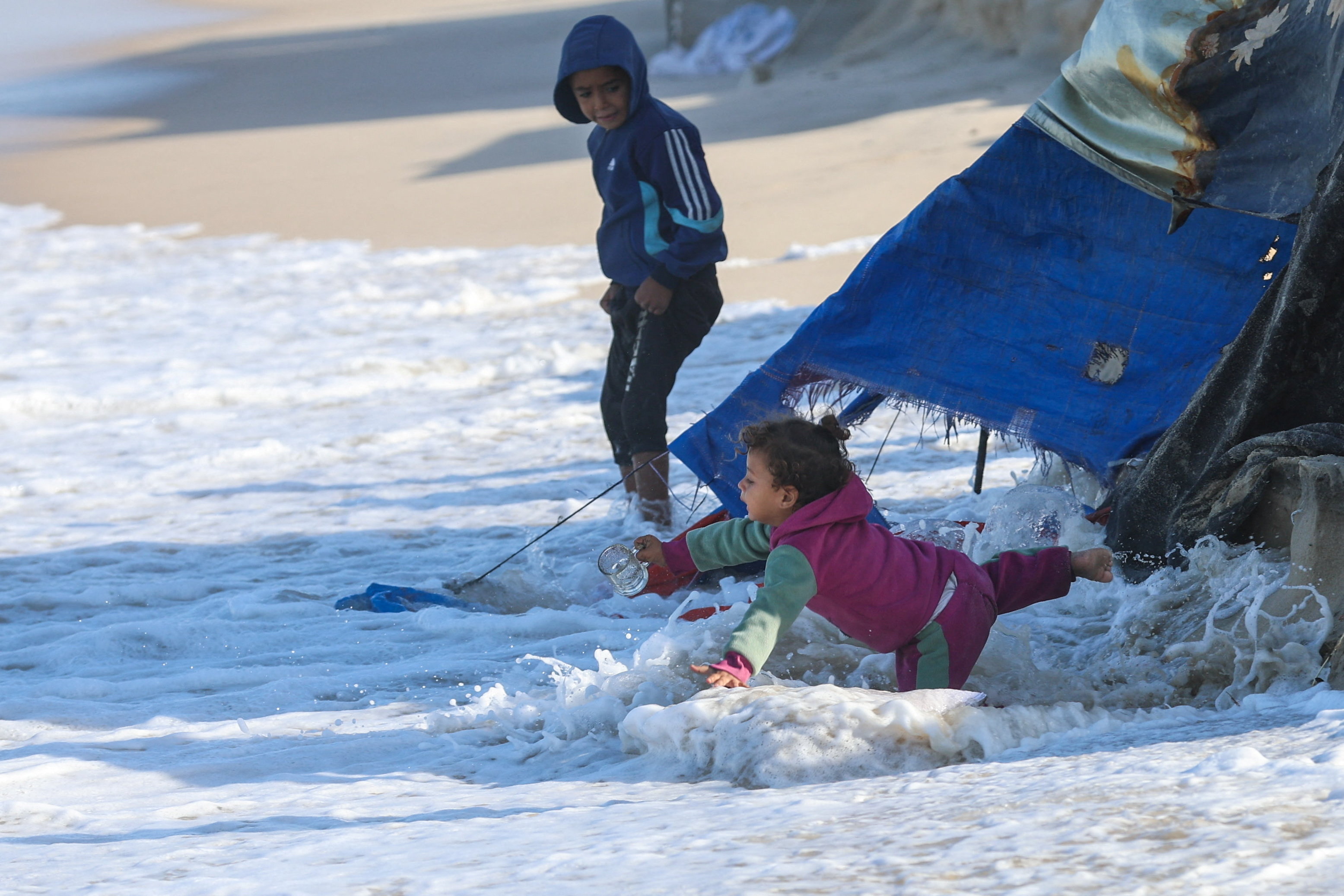 Children in Gaza fall into the sea as their makeshift tents are dragged into the water. 