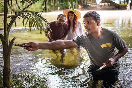 Aboriginal man waist deep in water with two guests in the background