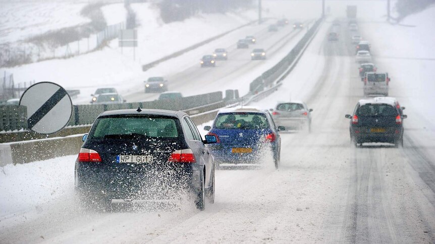 Cars drive on a snow-covered highway
