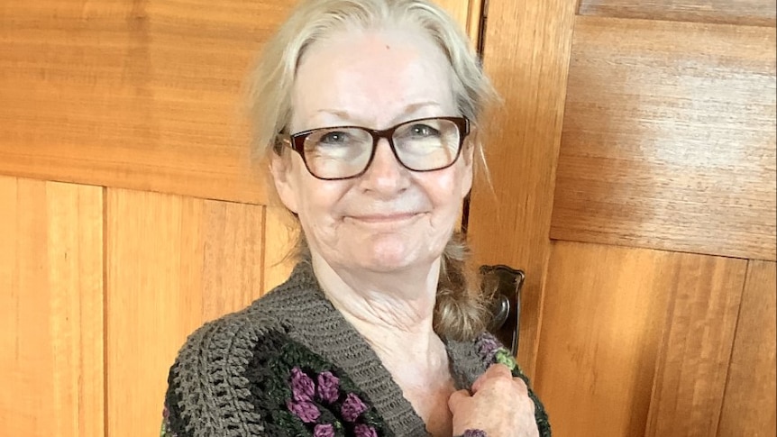 A woman wearing a crocheted cardigan poses for a photo