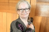 A woman wearing a crocheted cardigan poses for a photo