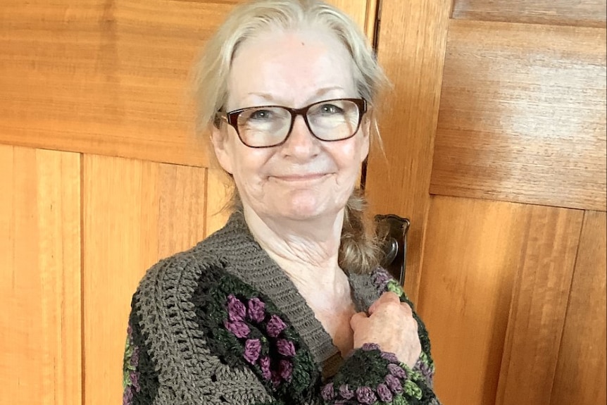 A woman wearing a crocheted cardigan poses for a photo