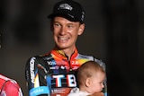 Enrica Mas, Primoz Roglic, with his son, and Jack Haig, with his baby, on the podium after the Vuelta a Espana.
