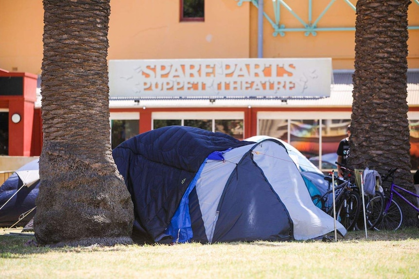 Une tente se trouve au premier plan, devant le théâtre de marionnettes de pièces de rechange