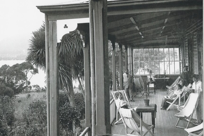 Photograph from the early 1900s of a wooden veranda with a family standing around