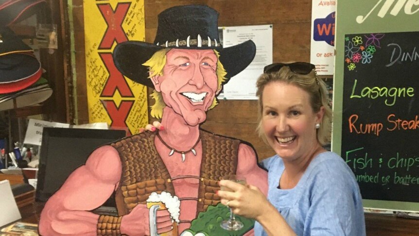 a woman standing next to a cutout of Crocodile Dundee.