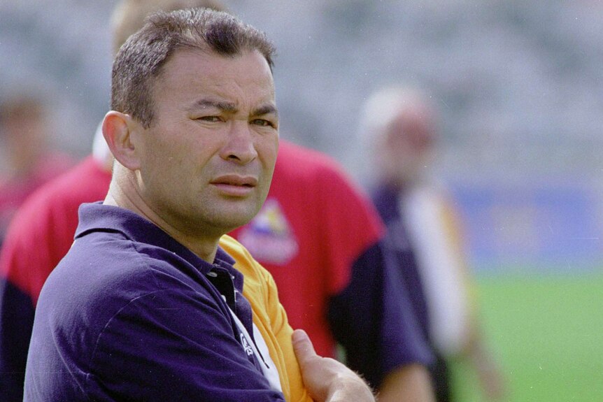A male rugby coach wearing a Brumbies polo shirt looks to his right.
