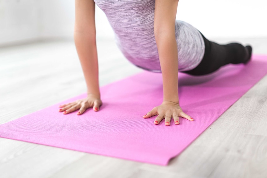 Woman doing yoga on mat depicting positive ways to spend your mental health day.