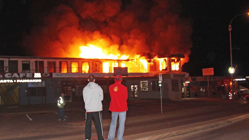 Locals watch as fire burns through a commercial complex at outback Coober Pedy.