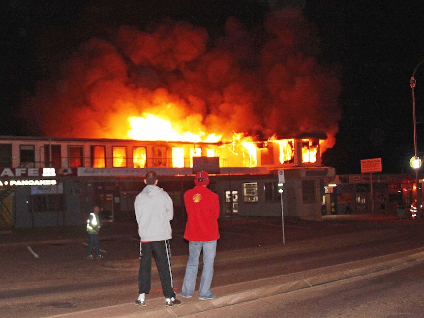 Locals watch as fire burns through a commercial complex at outback Coober Pedy.