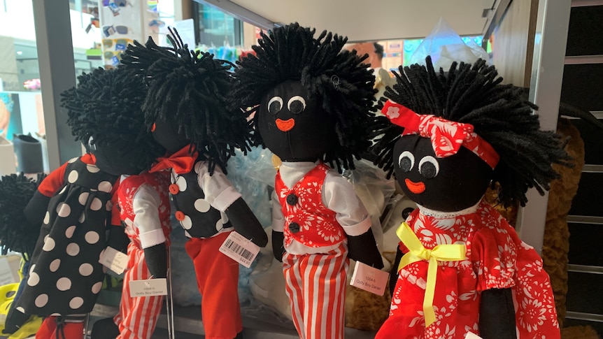 five gollywog dolls made of black fabric with frizzy hair and red and black clothing