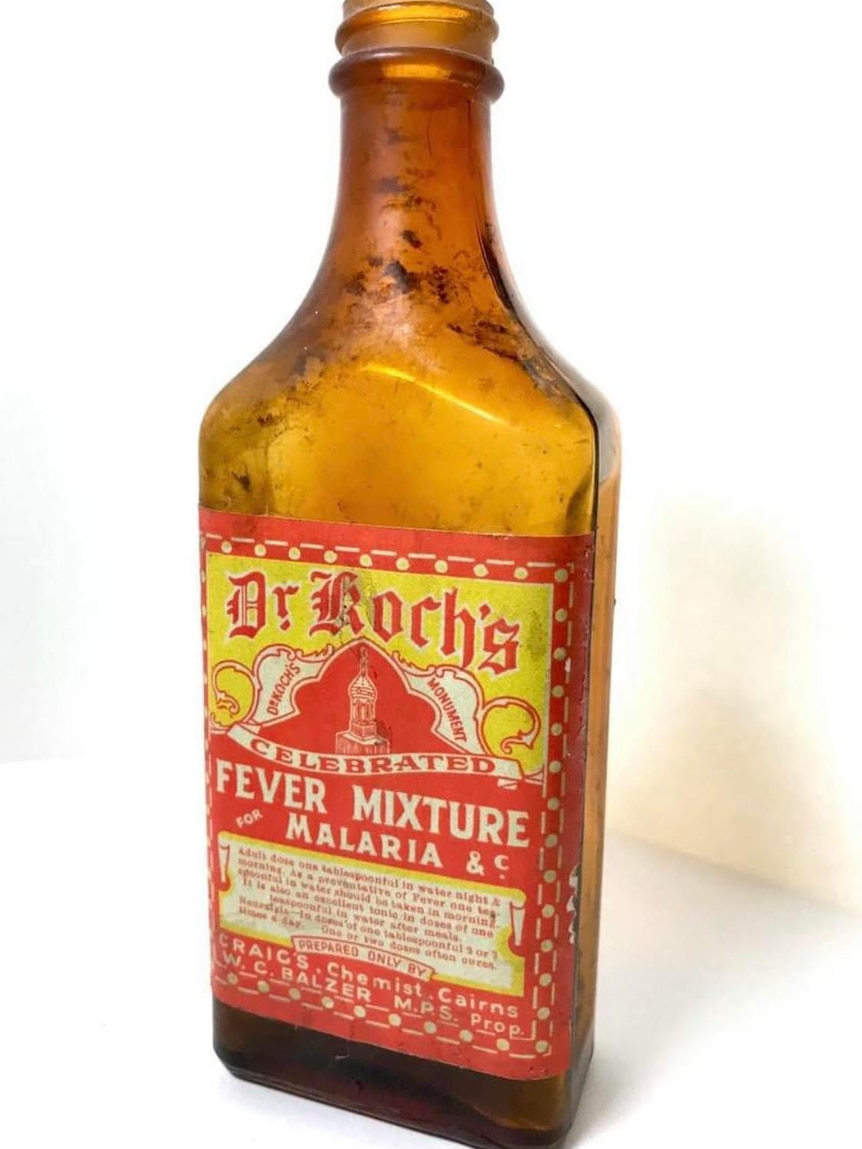 An old amber-coloured bottle with a yellow and red label saying Dr Koch's fever mixture. 