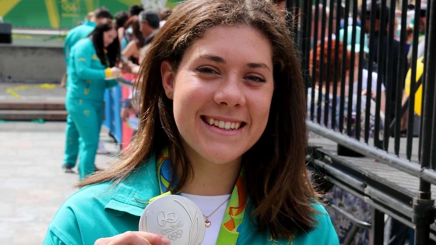Olympic swimmer Tamsin Cook holds up her silver Olympic medal.