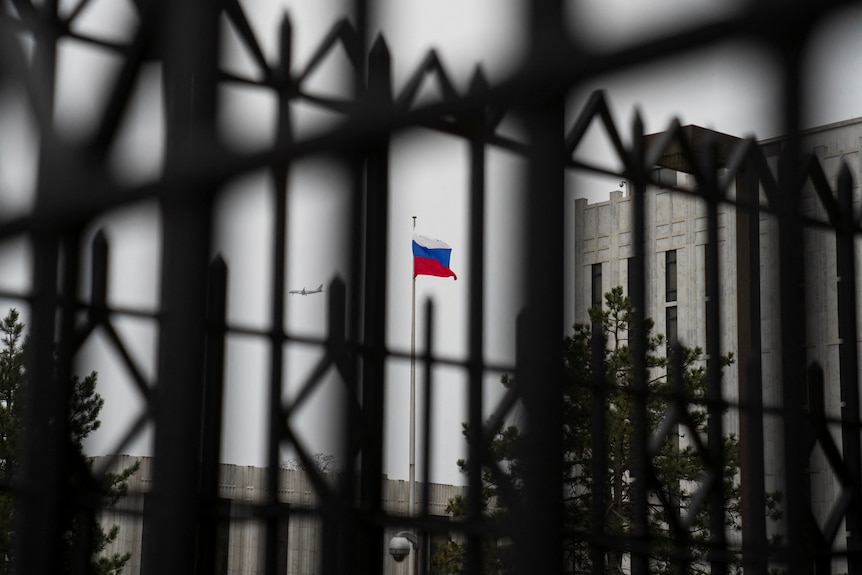 mirando a través de las puertas de la Embajada de la Federación Rusa en Washington DC mientras la bandera rusa ondea sobre ella