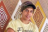 A young Indigenous man in a cap, smiling.