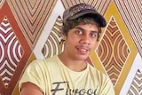 A young Indigenous man in a cap, smiling.