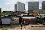 Two boys playing in a slum with skyscrapers behind them