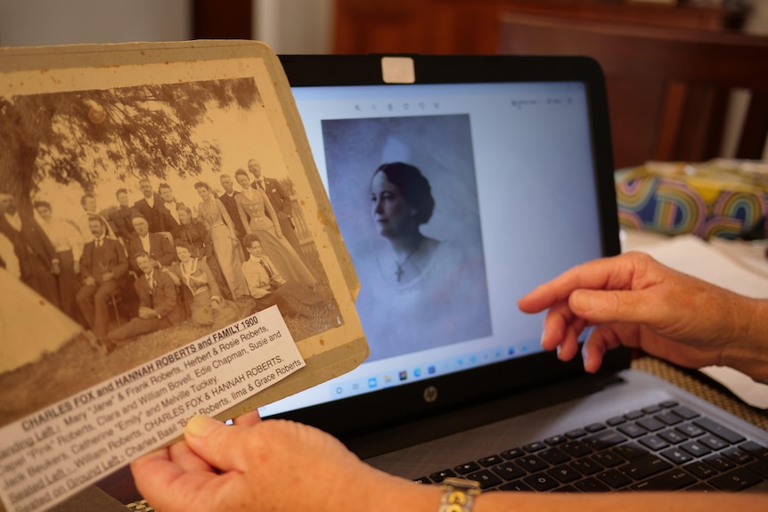 An old sepia photo in someone's hands by a computer screen