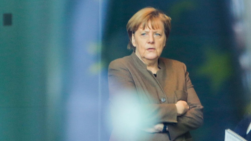 German chancellor Angela Merkel stands behind glass at the chancellery in Berlin, on January 14, 2016.