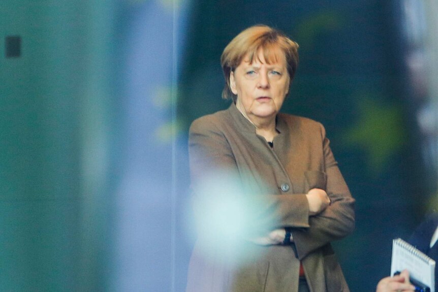 German chancellor Angela Merkel stands behind glass at the chancellery in Berlin, on January 14, 2016.