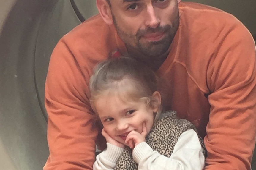 Jordan Kotarac sits on some play equipment with his daughter Juliette.