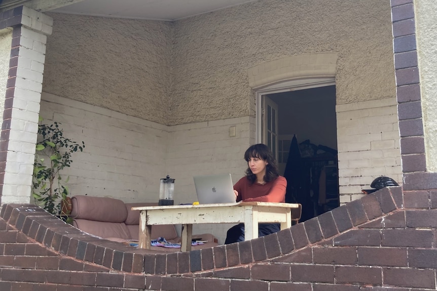 a woman on a laptop on a balcony