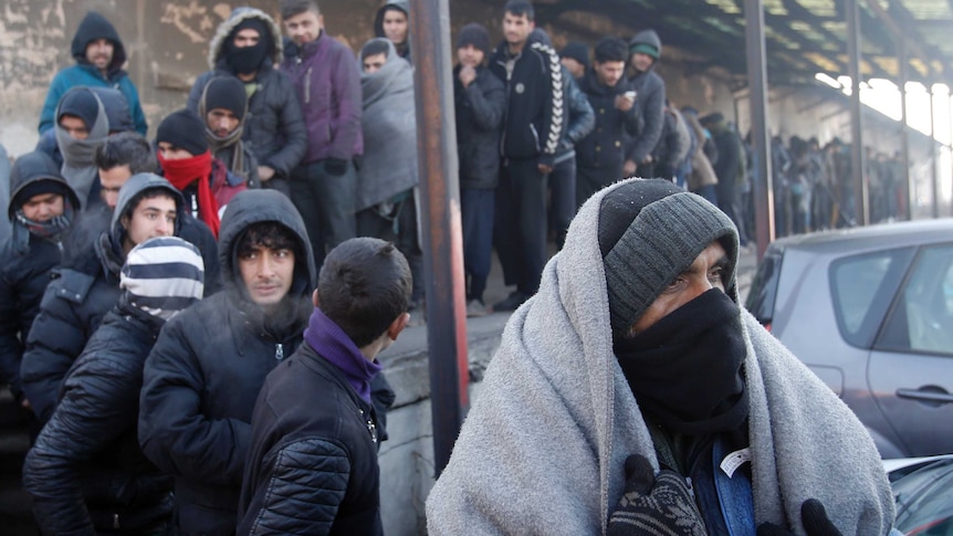 Asylum seekers queue for food in front of an abandoned warehouse in Belgrade, Serbia.