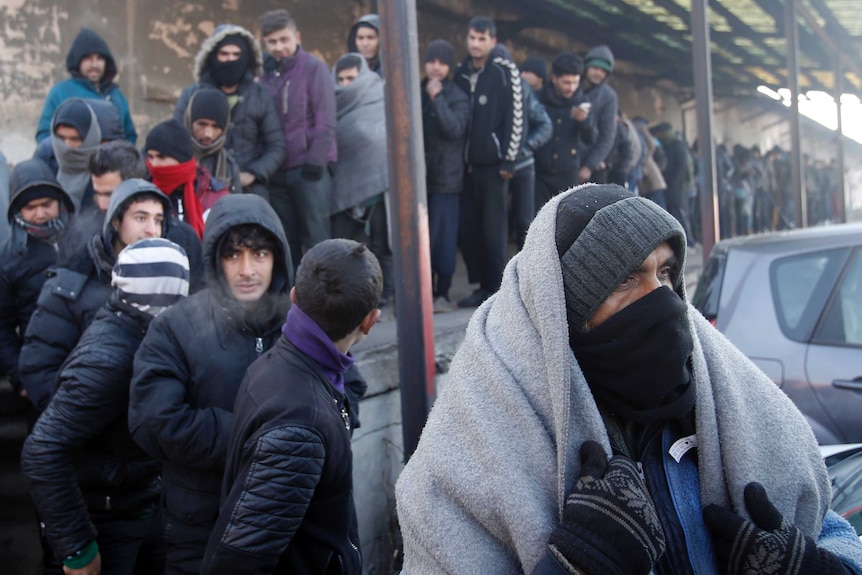 Asylum seekers queue for food in front of an abandoned warehouse in Belgrade, Serbia.