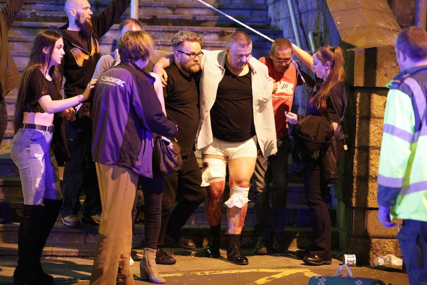 Bystanders assist an injured man near the Manchester Arena.