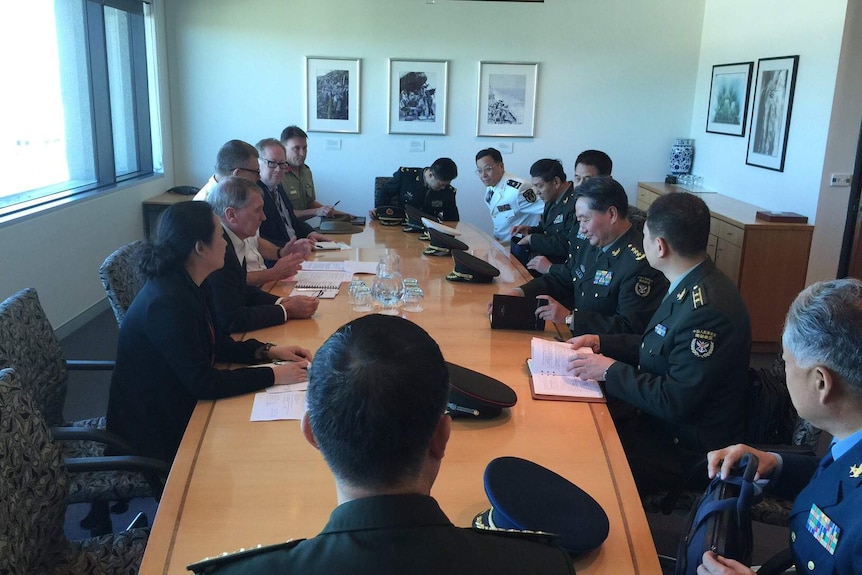 Men and women in uniform meet around a table