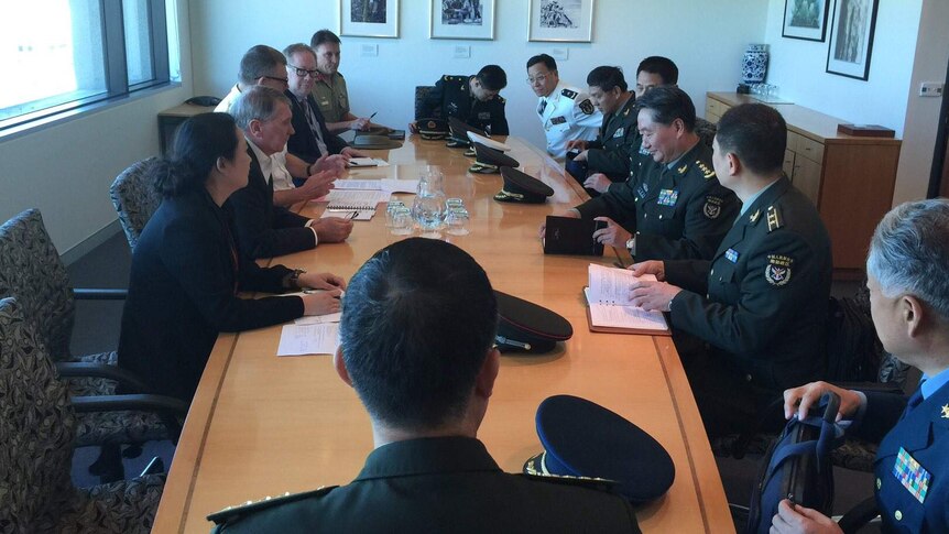 Men and women in uniform meet around a table