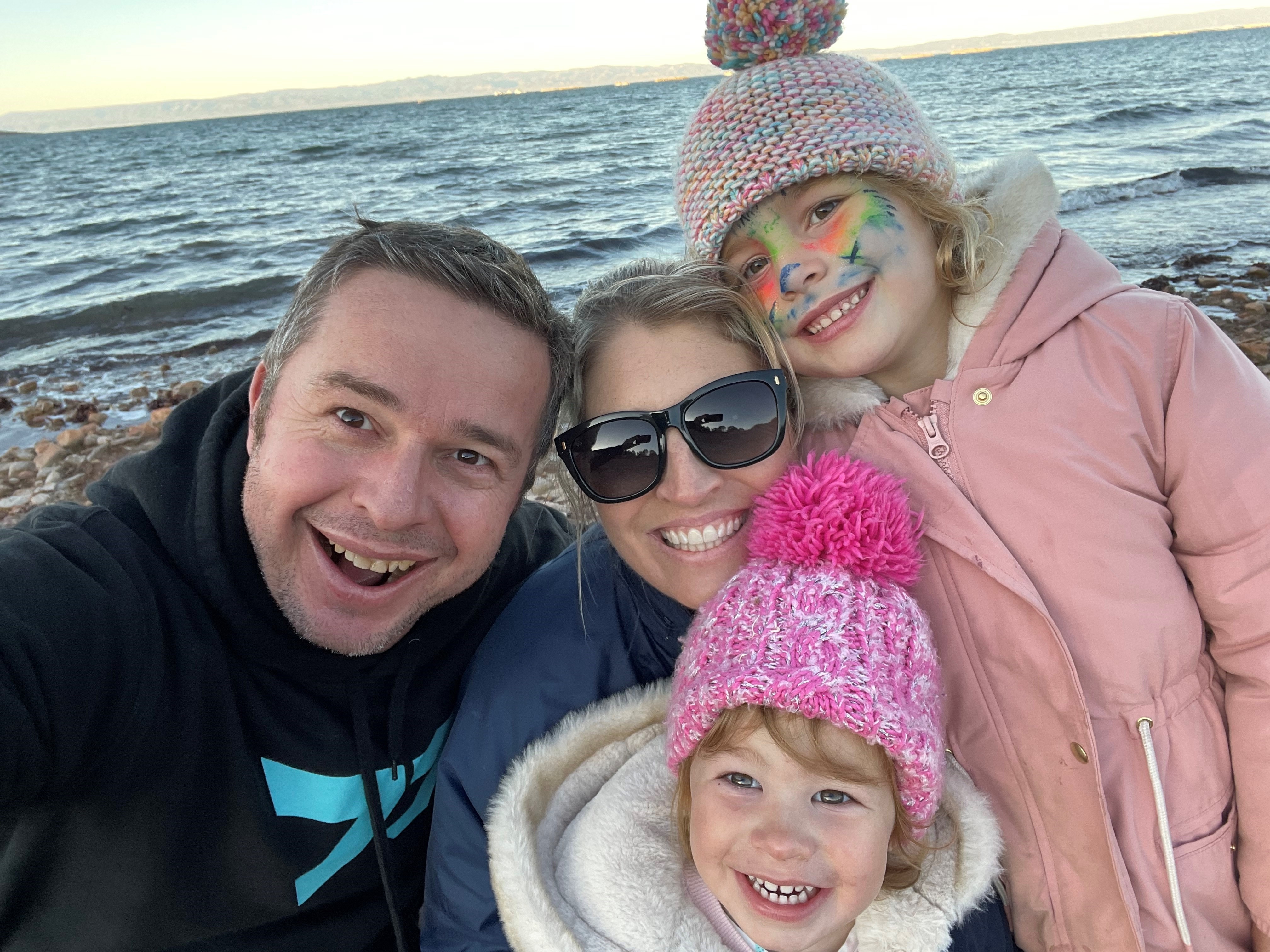 A family of four taking a selfie in front of the ocean.
