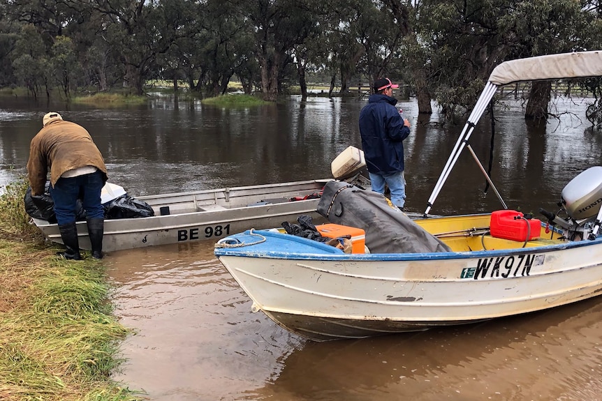 Two boats moored by a dry piece of land surrounded by floodwater