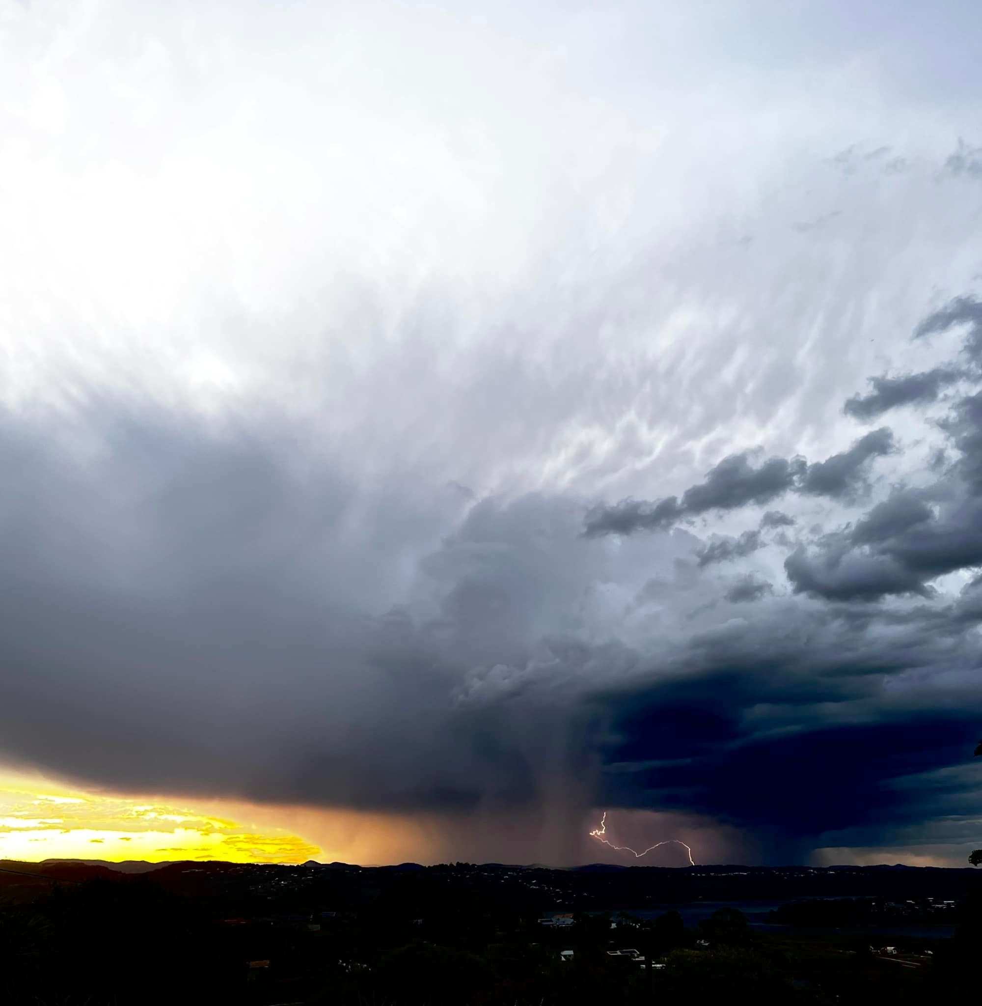 Storm cells range with lightning thunder before a golden sunset glow