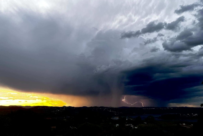 Storm cells range with lightning thunder before a golden sunset glow