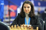 Sara Khadem of Iran sits in front of a chess board.